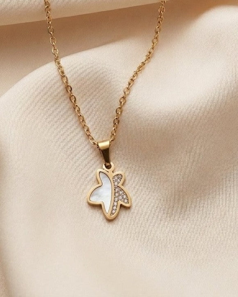 Gold necklace with a butterfly pendant on a beige fabric background