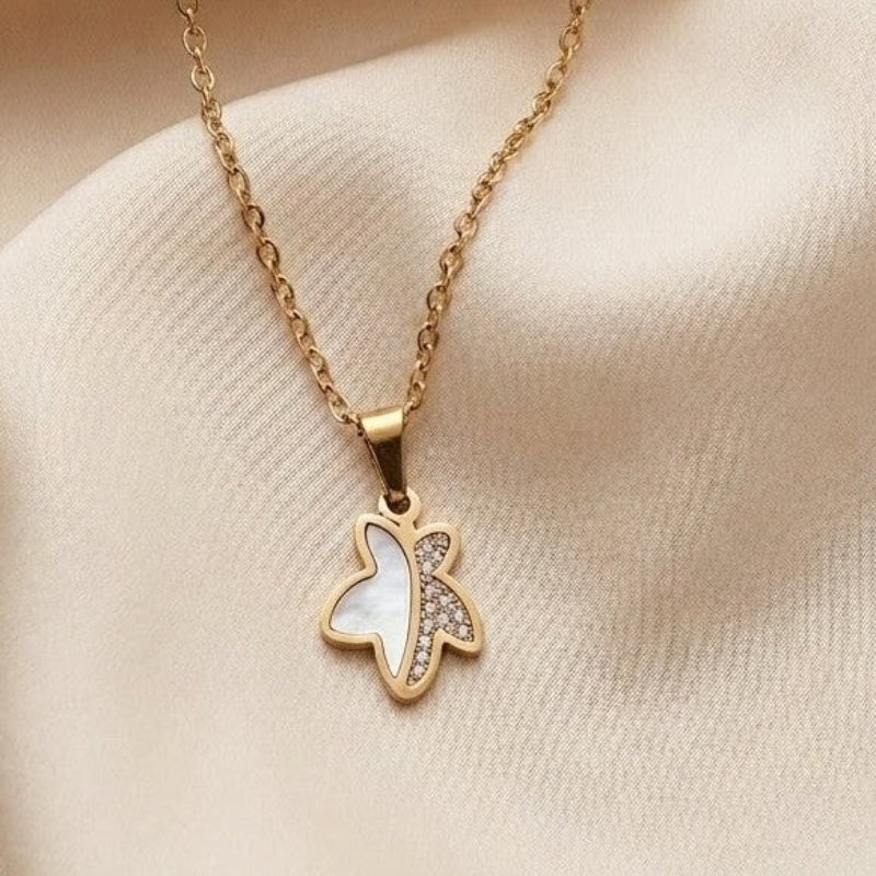 Gold necklace with a butterfly pendant on a beige fabric background