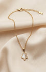 Gold necklace with a butterfly pendant on a beige fabric background