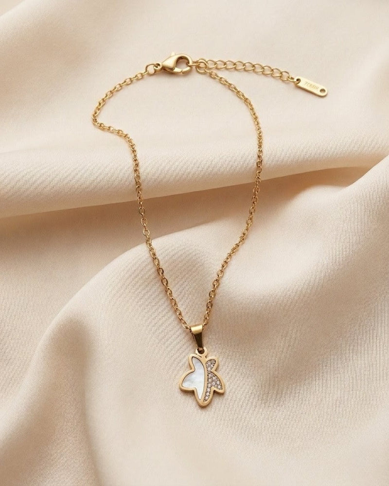 Gold necklace with a butterfly pendant on a beige fabric background