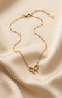Gold necklace with a bow pendant on a beige fabric background
