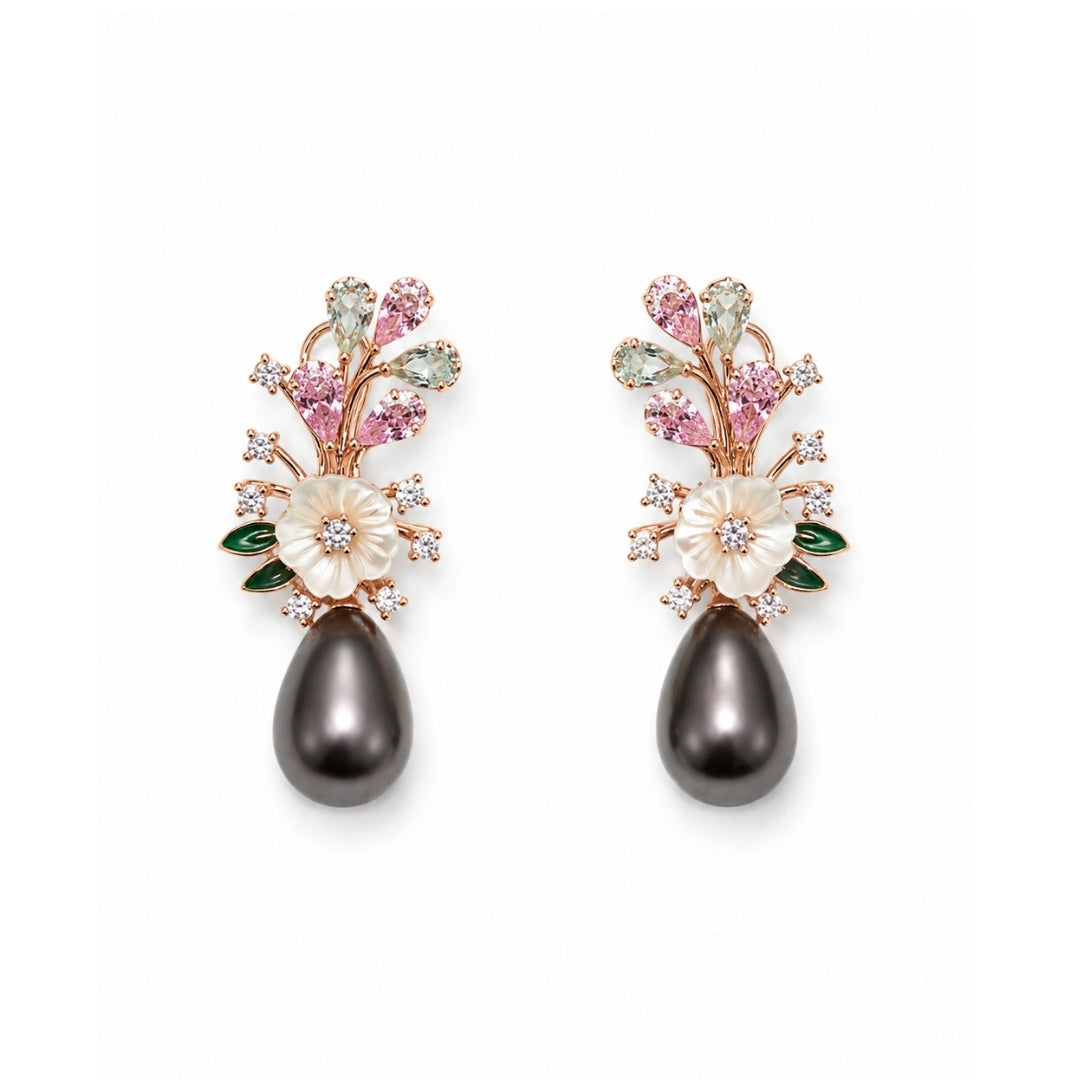A pair of floral drop silver 925 earrings featuring white mother-of-pearl flowers, pink and green gemstone accents, rose gold metal, and a dangling dark gray teardrop pearl at the bottom, set against a plain white background.