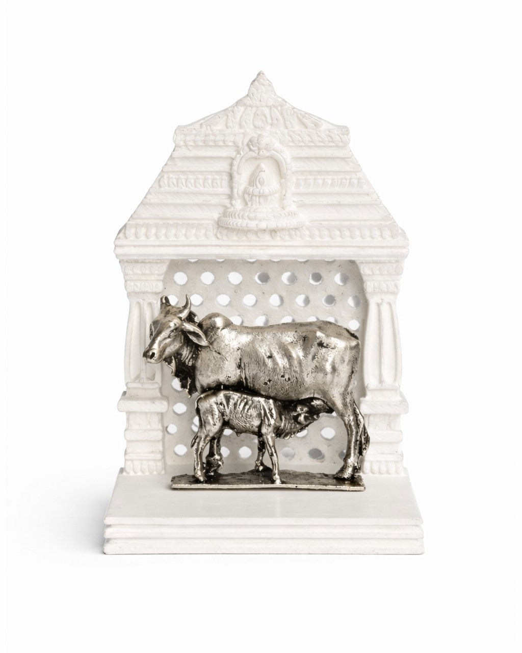 Decorative silver sculpture of a cow and calf in a white architectural temple setting on a white background