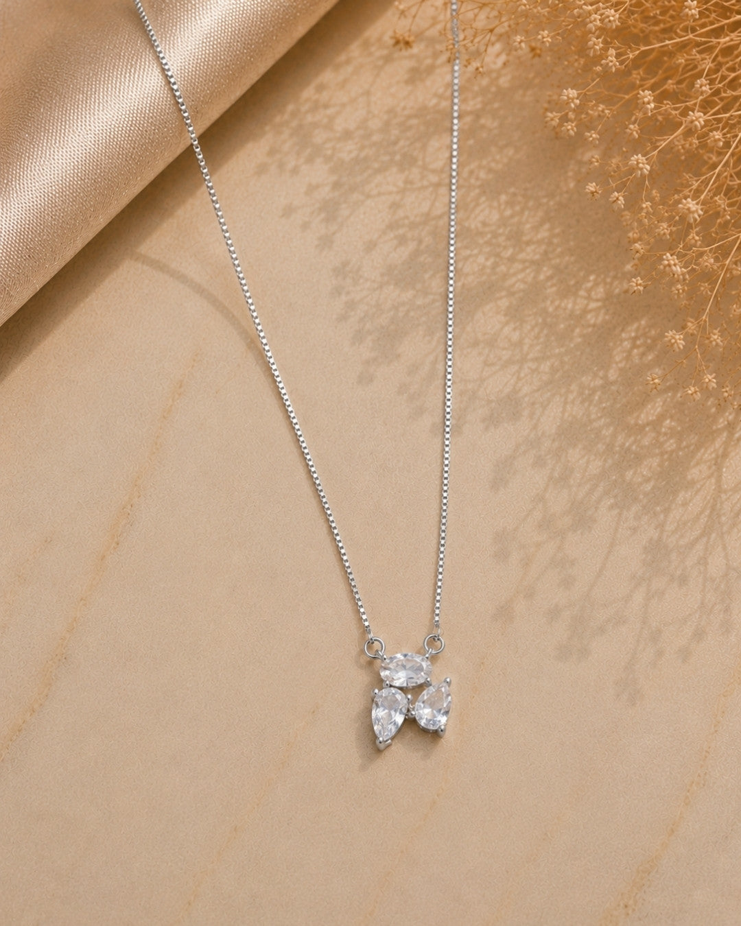 Silver 925 necklace with a leaf-shaped pendant on a beige fabric background