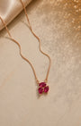 Rose gold necklace with red gemstones on a beige surface