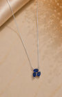 Silver necklace with a blue pendant on a beige surface
